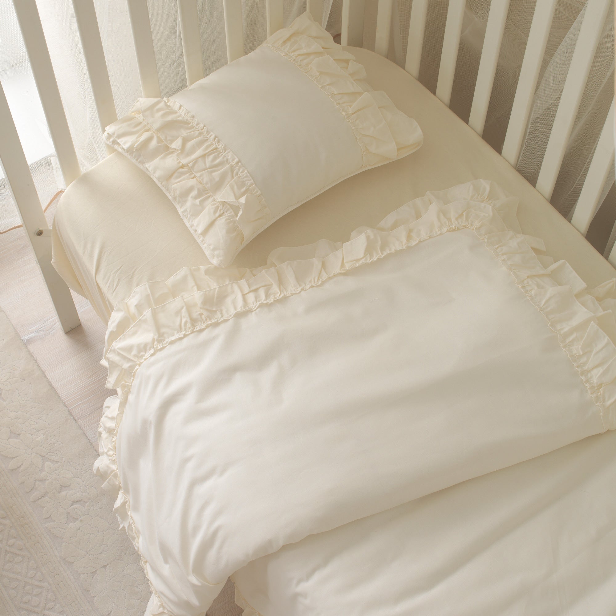 Pürüzsüz dokulu krem pamuk kumaşın ve zarif fırfır detaylarının yakın çekimi.