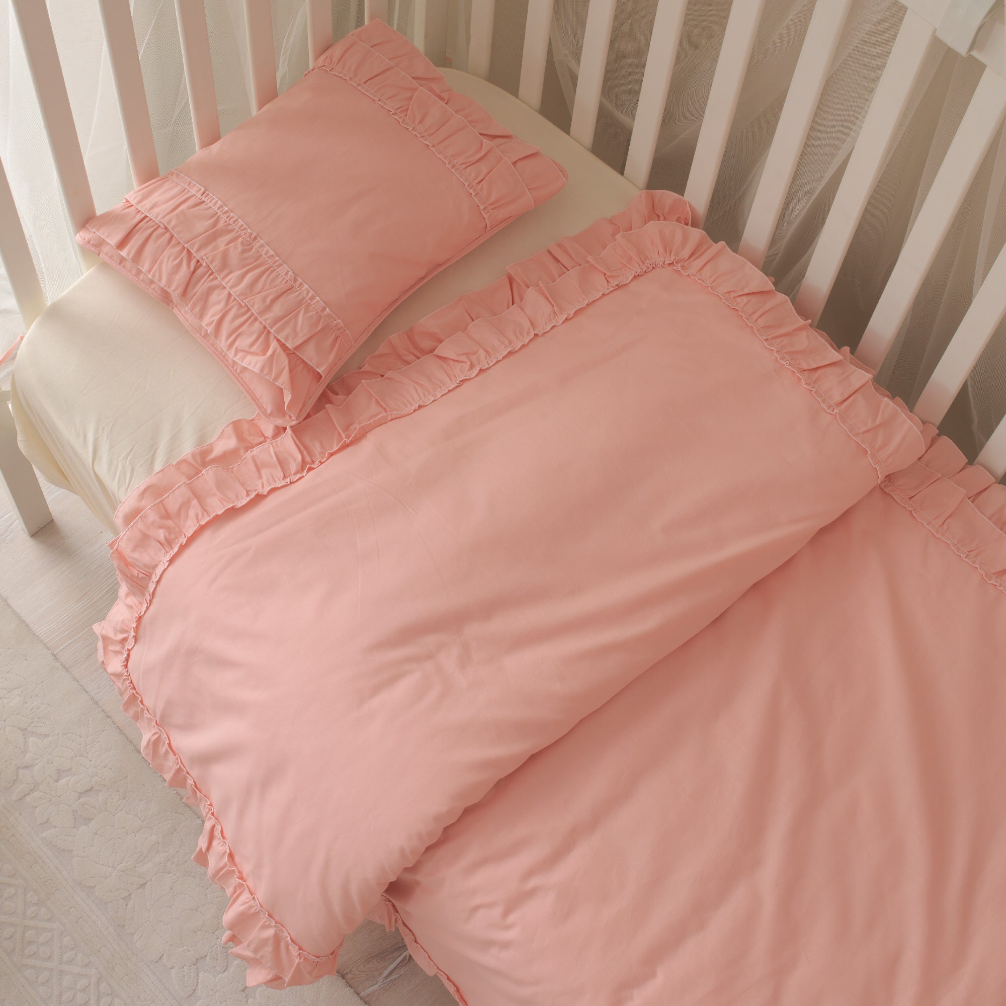 Pürüzsüz dokulu pembe pamuk kumaşın ve zarif fırfır detaylarının yakın çekimi.