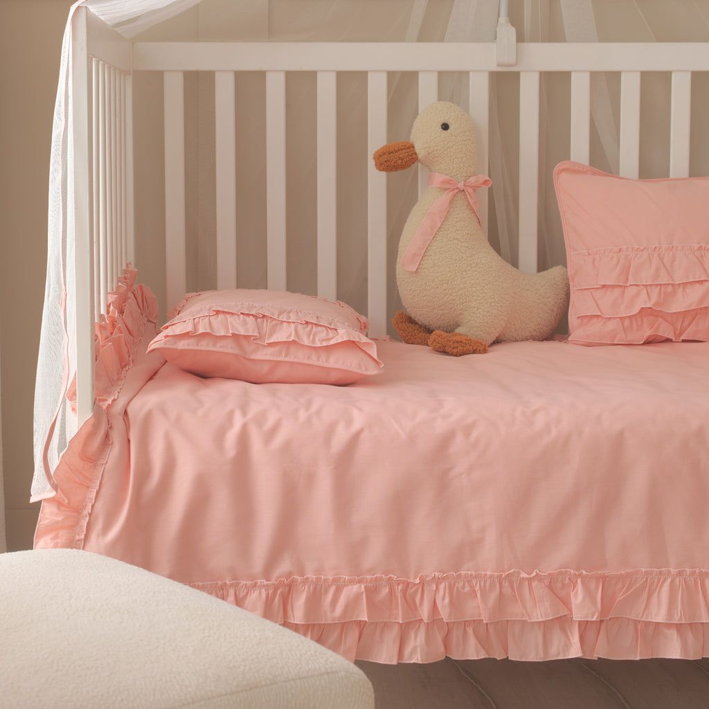 Şık pembe fırfırlı yastık kılıfı ve dekoratif bebek odası tekstil ürünleri.