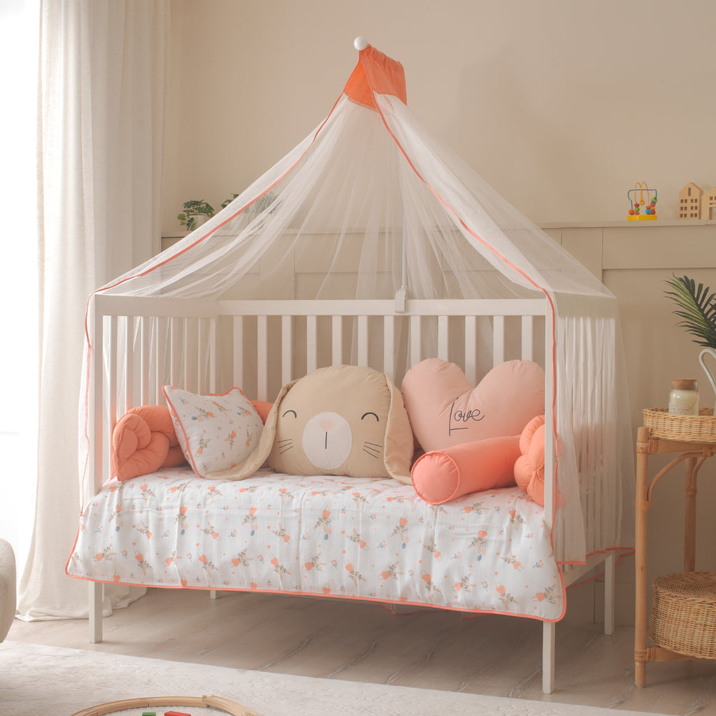 Mercan rengi örgü korumalı ve tavşan figürlü dekoratif bebek beşiği tasarımı.