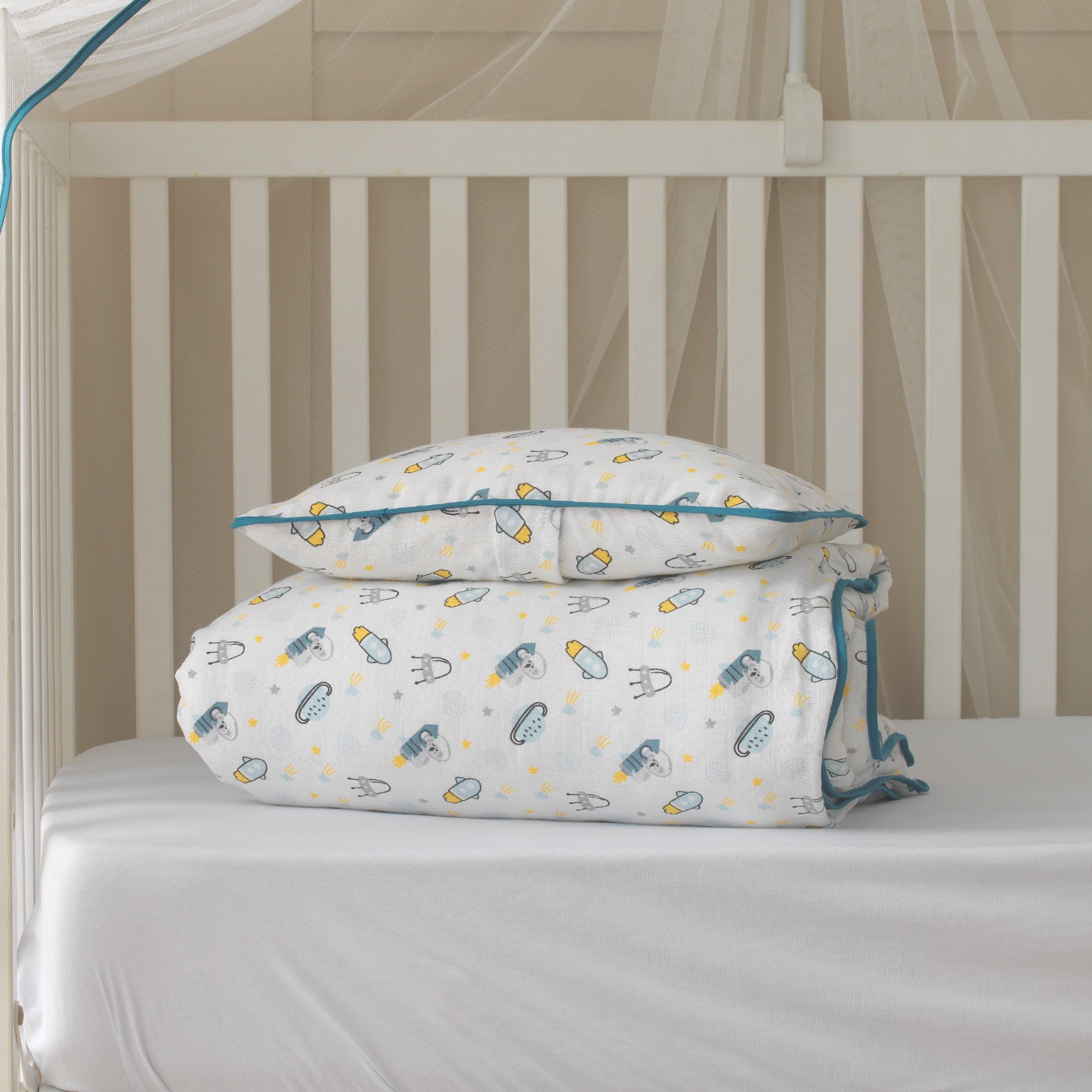 Uzay temalı roket desenli müslin bebek nevresim takımı ve mavi biyeli yastık kılıfı.